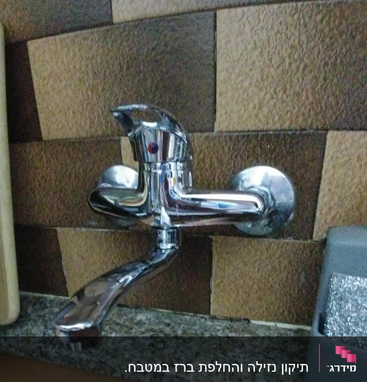 ברז כרום מותקן על קיר אריחים חומים